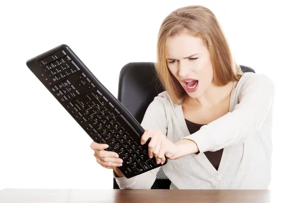 Schöne lässige Frau versucht, die Tastatur zu zerstören. — Stockfoto