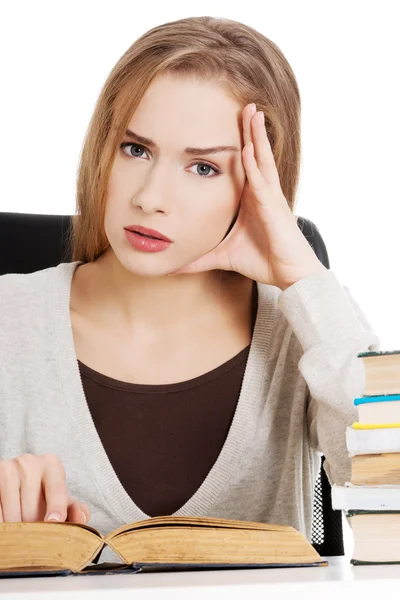 Hermosa estudiante casual sentada junto a una pila de libros — Foto de Stock