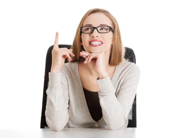 Beautiful casual woman sitting and pointing up, advertising. — Stock Photo, Image