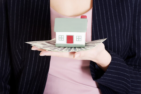 Beautiful business woman holding dollar currency and house.