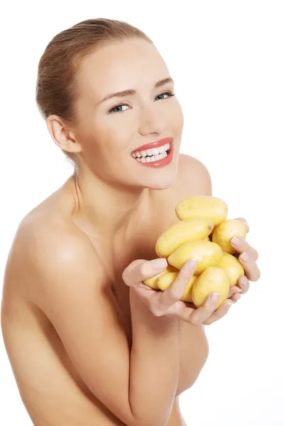 Beautiful naked caucasian woman is holding fresh, raw potatoes. — Stock Photo, Image