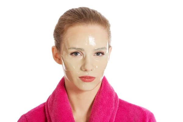Vacker kvinna i rosa morgonrock och havinf ansiktsmask. — Stockfoto