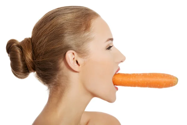 Beautiful profile of caucasian woman eating raw fresh carrot. Stock Image