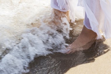 Pictore of feet on a beach and water. clipart
