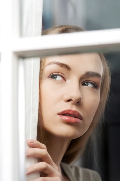 美丽的女人正透过窗户看. — 图库照片