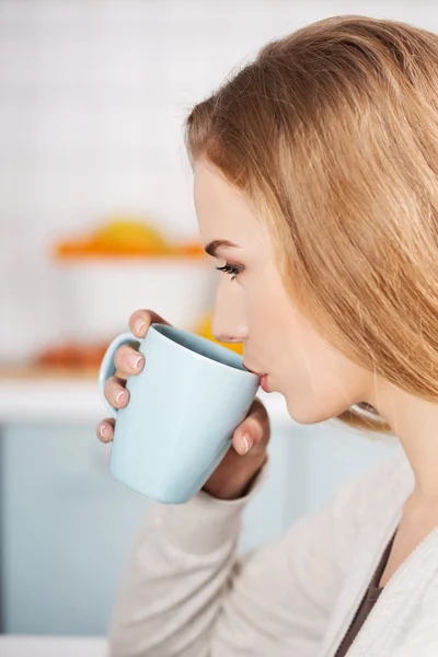 Beautiful caucasian woman is drinking hot drink — Stock Photo, Image