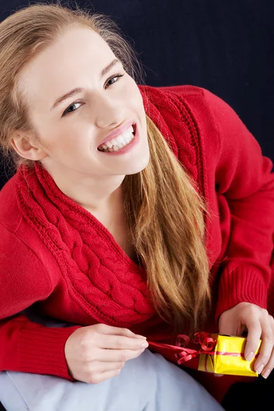 Bella donna caucasica in maglione rosso è scartare piccolo regalo — Foto Stock