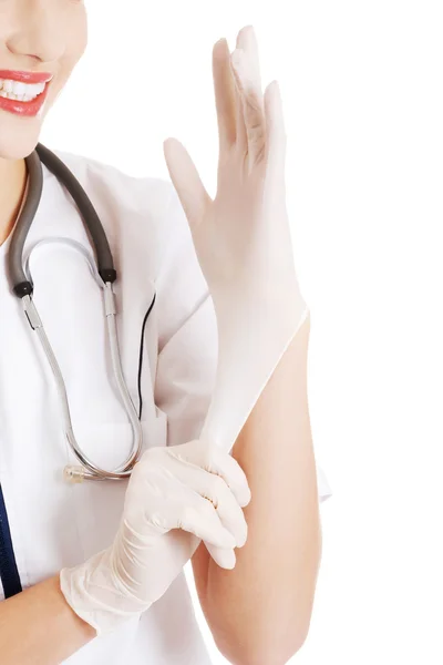 Mooie jonge arts of verpleegkundige zetten steriele handschoenen. — Stockfoto