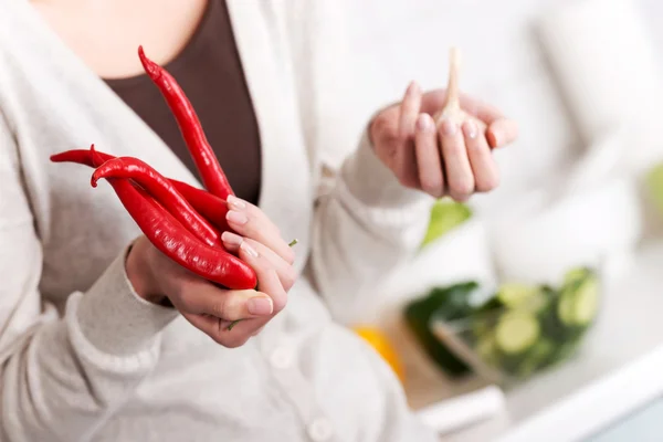Beautiful caucasian woman is holding chili peppers and garlic. — Stock Photo, Image
