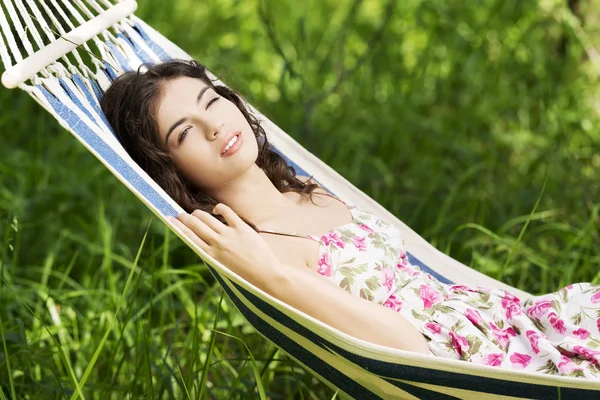 Young woman in cocktail dress relaxing in a hammock. — Stock Photo, Image
