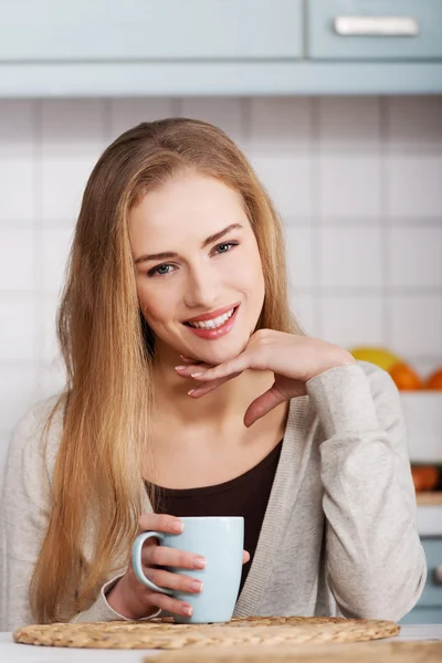 Beautiful caucasian woman is sitting by table with cup of coffee — Stock Photo, Image