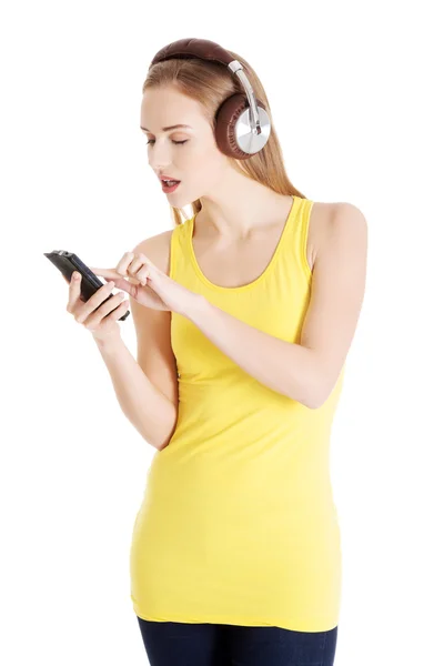Mulher casual bonita no topo amarelo está ouvindo música . — Fotografia de Stock