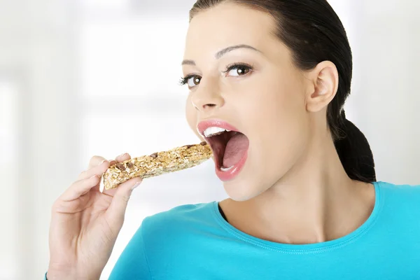 Young woman eating Cereal candy bar — Stock Photo, Image