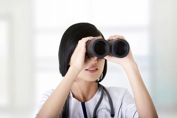 Atractive fille médicale regardant à travers les jumelles — Photo