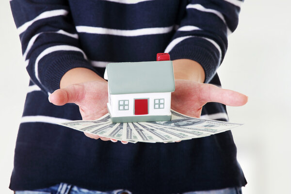 Женщина держит доллары США купюры и дом
