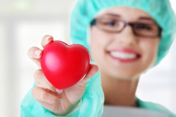 Smiling female doctor or nurse holding heart — Stock Photo, Image