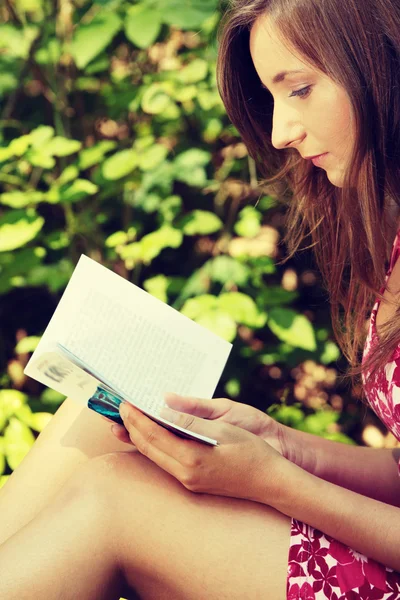 Mulher de leitura que coloca em um banco de parque . — Fotografia de Stock