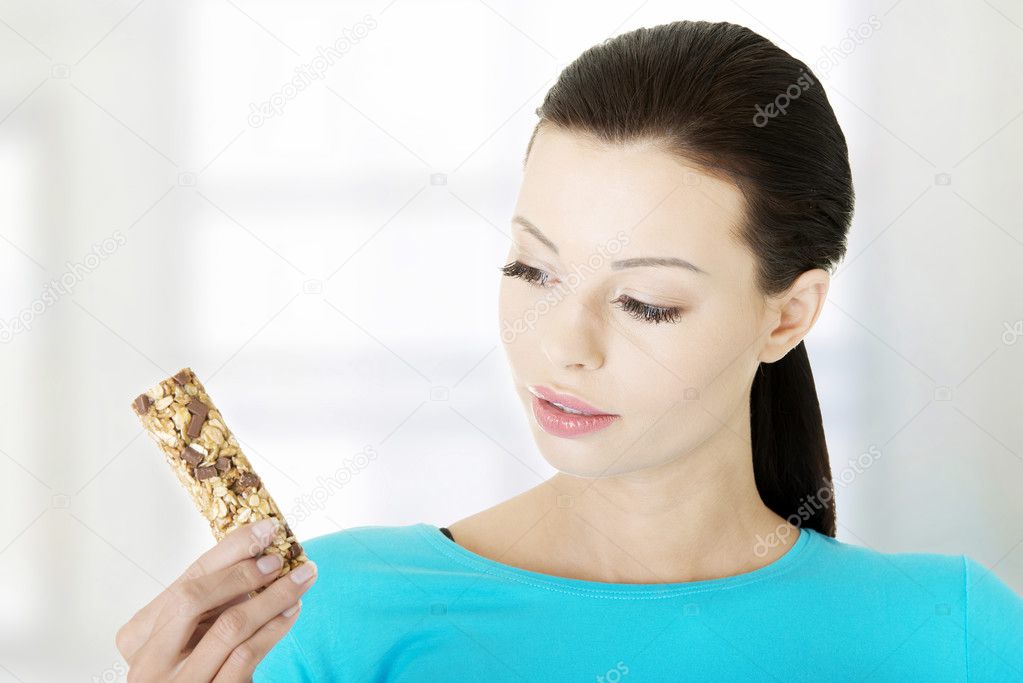 Young woman eating Cereal candy bar