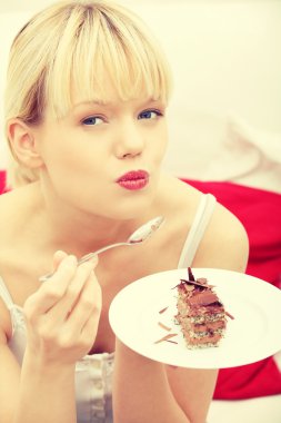 güzel bir kadın kanepede pasta yemeye.