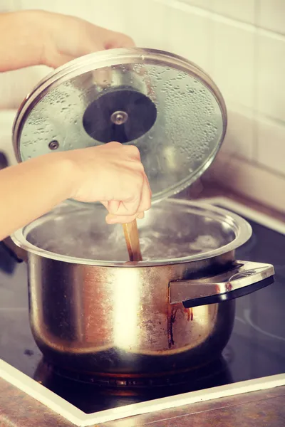 Ung kvinna koka något i potten — Stockfoto