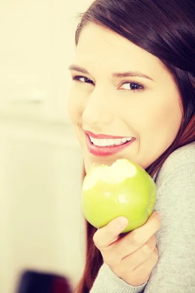 Donna in cucina mangiare mela verde — Foto Stock