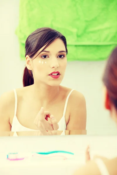 Hermosa mujer aplicando crema en la cara — Foto de Stock