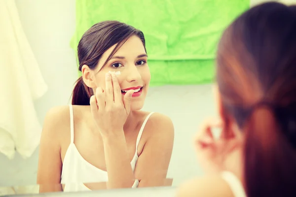 Beautiful woman applying cream on face — Stock Photo, Image