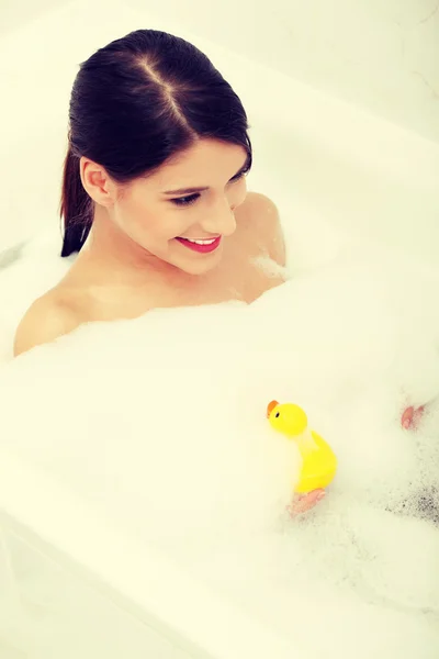 Mujer tomando un baño con pato amarillo . —  Fotos de Stock