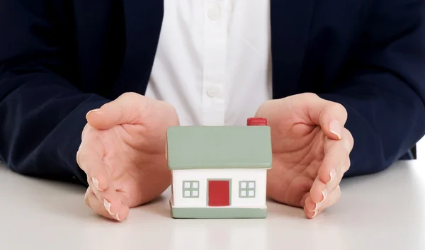 Close up on house model between hands on table. Stock Photo