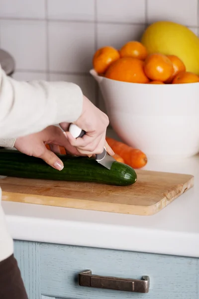 Caucasian attractive young woman is cutting cucumber. — Stock Photo, Image