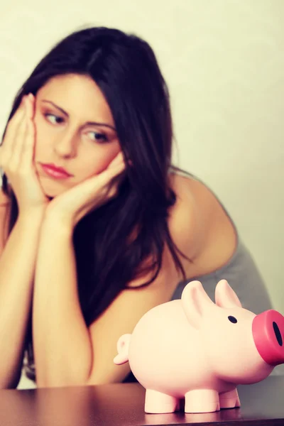 Vrouw kijken naar piggy bank — Stockfoto