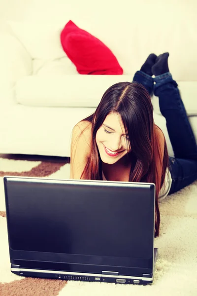 Joven hembra acostada en el suelo usando laptop . — Foto de Stock