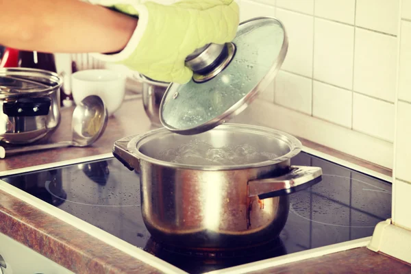 Jonge vrouw koken iets in pot — Stockfoto