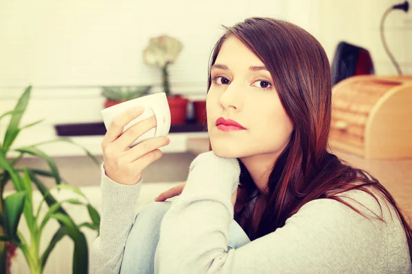 Mujer joven tomando café o té en la cocina —  Fotos de Stock