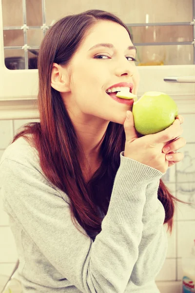 Donna in cucina mangiare mela verde — Foto Stock