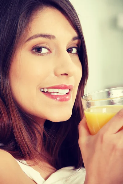 Mulher na cama bebendo suco de laranja — Fotografia de Stock