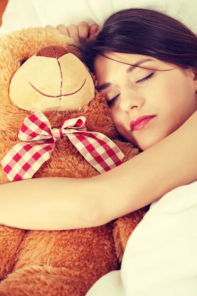 迷人的黑发姑娘和她的泰迪熊躺在床上 — 图库照片