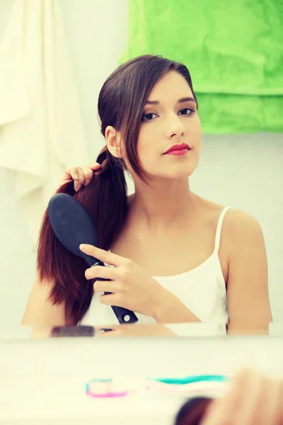 Красива молода жінка чистить волосся — стокове фото
