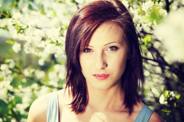 Çiçek açan ağaçların arasında genç bir kadın.