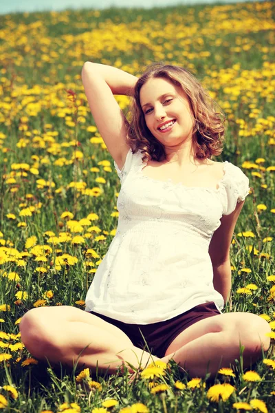 Młoda kobieta siedzi na kwitnącej łące.. — Zdjęcie stockowe