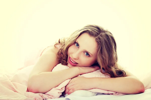 Mooie vrouw ligt in bed met pillow. — Stockfoto