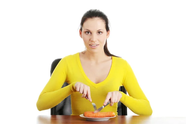 Jonge vrouw eten wortel van plaat — Stockfoto