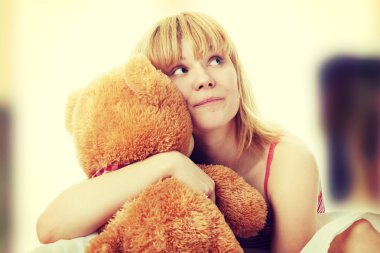 yatakta sarışın çocuğu sevimli ayıcık kucaklar