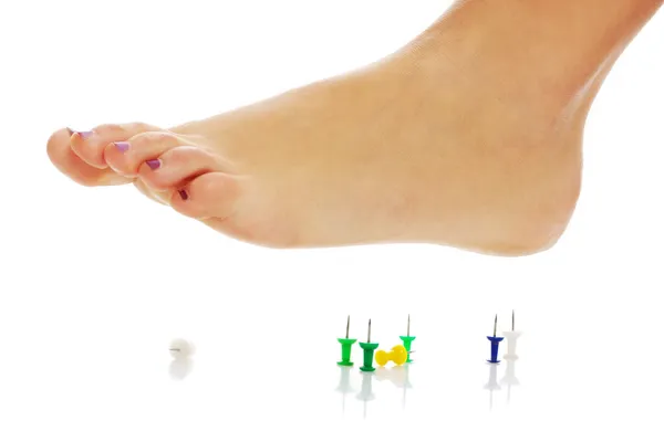 Female foot above pushpin — Stock Photo, Image