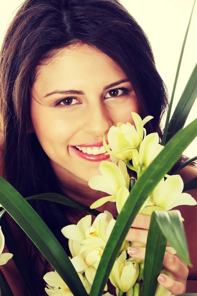 Bella giovane donna che profuma fiore di orchidea — Foto Stock