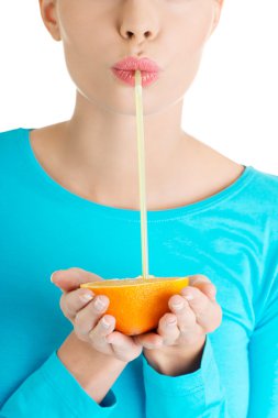 Genç bir kadın portakal suyu içiyor.