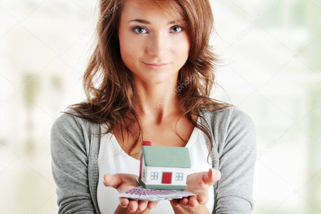 Woman holding euros bills and house model 