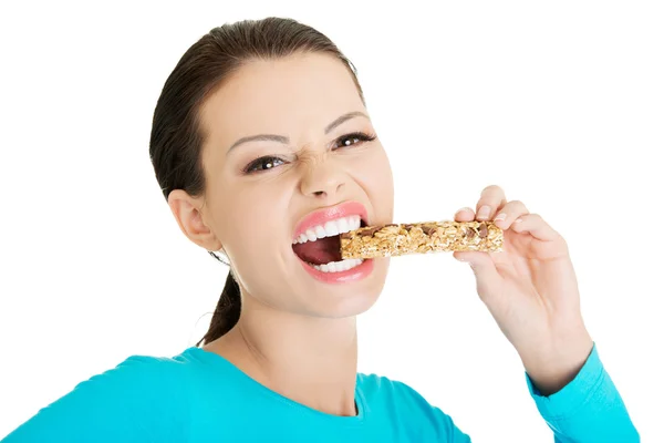Ung kvinna äta spannmål chokladkaka — Stockfoto