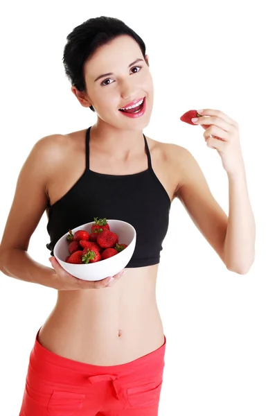 Vrij fit vrouw eten aardbeien Stockafbeelding