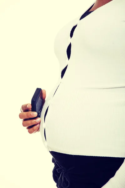 Mulher grávida segurando um celular contra a barriga . — Fotografia de Stock